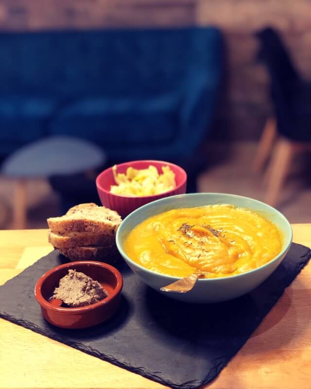 photo d'un repas avec une soupe de courge dans un bol, du paté vegan avec du pain et une salade d'endives